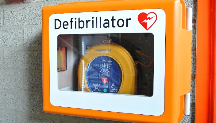 Defibrillator in Defibrillatorkasten an Wand.